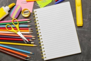 Siyah karatahta arka planında çeşitli ofis ve okul malzemeleriyle okul konseptine geri dönelim..