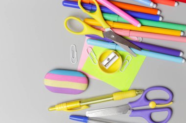 Gri arka planda çeşitli ofis ve okul malzemeleriyle okul konseptine geri dönüyoruz..