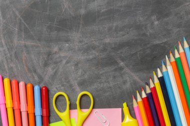 Siyah karatahta arka planında çeşitli ofis ve okul malzemeleriyle okul konseptine geri dönelim..