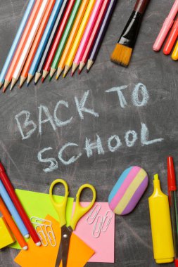 Siyah karatahta arka planında çeşitli ofis ve okul malzemeleriyle okul konseptine geri dönelim..