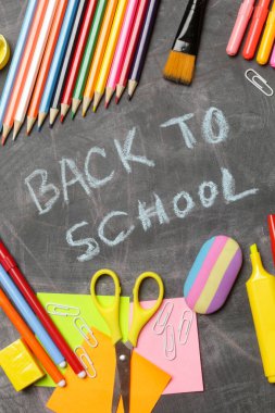 Siyah karatahta arka planında çeşitli ofis ve okul malzemeleriyle okul konseptine geri dönelim..
