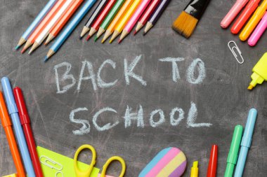Siyah karatahta arka planında çeşitli ofis ve okul malzemeleriyle okul konseptine geri dönelim..