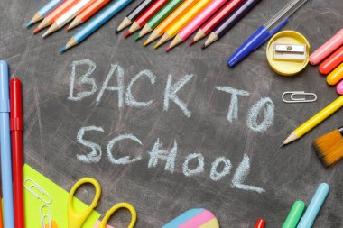 Siyah karatahta arka planında çeşitli ofis ve okul malzemeleriyle okul konseptine geri dönelim..