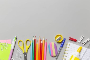 Gri arka planda çeşitli ofis ve okul malzemeleriyle okul konseptine geri dönüyoruz..