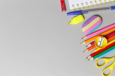 Gri arka planda çeşitli ofis ve okul malzemeleriyle okul konseptine geri dönüyoruz..