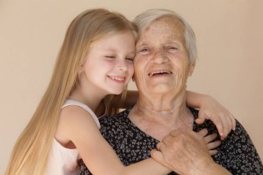 Mutlu aile, çocuk ve büyük büyükanne kucaklaşır, rahatlar, gülümser, sever ve bağlanır, evde mutlu ve mutlu bir şekilde sevgi ve şefkat gösterirler.