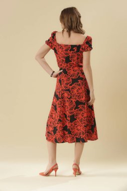 Stüdyo fotoğrafları. Siyah ve turuncu Midi elbiseli, kısa kabarık kollu genç bir kadın model.