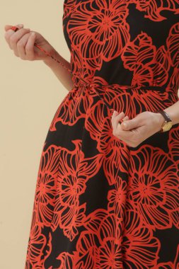 Stüdyo fotoğrafları. Siyah ve turuncu Midi elbiseli, kısa kabarık kollu genç bir kadın model.