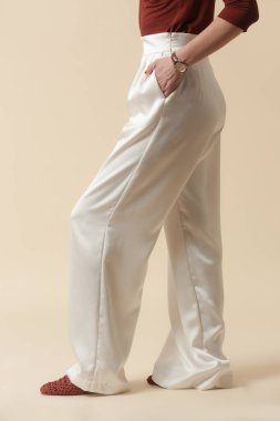 Geniş ipek beyaz pantolon giyen bir kadın model. Klasik ve zamansız basit moda. Stüdyo çekimi.