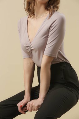 Bej renkli pamuklu gömlek giyen ve şık siyah pantolon giyen bir manken. Moda stüdyosu çekimi.