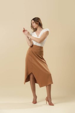Beyaz yaz bluzu ve kahverengi ipek etek giyen kadın model. Moda stüdyosu çekimi.