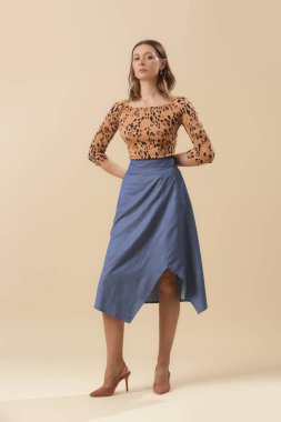Hayvan desenli gömlek ve mavi etek giyen kadın model. Moda stüdyosu çekimi.