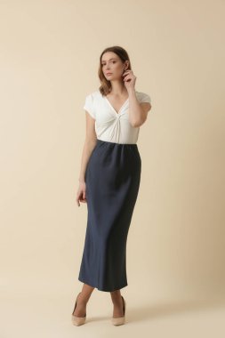 Beyaz yaz bluzu ve mavi ipek etek giyen kadın model. Moda stüdyosu çekimi.