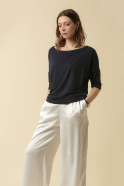 Siyah bluz ve beyaz pantolon giyen bir manken. Klasik ve basit moda. Stüdyo çekimi.