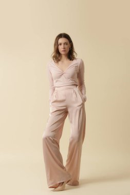 Tek renkli pembe elbise giyen bir kadın manken. Klasik ve zamansız basit bluz ve geniş bacak pantolonu. Moda stüdyosu çekimi.