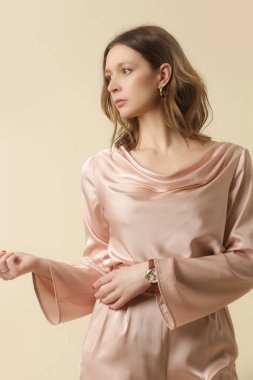 Tek renkli pembe elbise giyen bir kadın manken. Klasik ve zamansız basit bluz ve geniş bacak pantolonu. Moda stüdyosu çekimi.