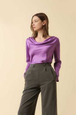 Mor ipek bluz giyen kadın model ve özel dikim gri pantolon. Klasik ve zamansız basit moda. Stüdyo çekimi.
