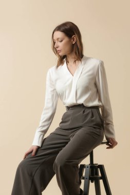 Beyaz bluz ve gri pantolon giyen bir kadın manken. Klasik iş, basit moda. Stüdyo çekimi.