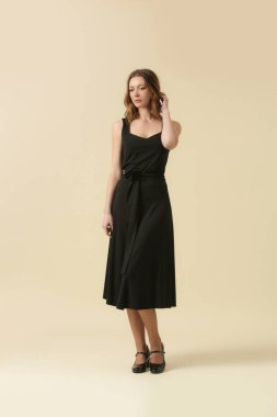  Siyah elbiseli bir kadın model. Klasik kolsuz bluz ve geniş midi etek. Moda stüdyosu çekimi.
