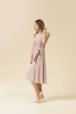  Tek renkli pembe elbise giyen bir kadın manken. Klasik kolsuz bluz ve geniş midi etek. Moda stüdyosu çekimi.