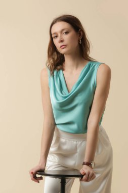 İpek elbise giyen kadın model, kolsuz kolsuz üst ve beyaz pantolon. Klasik ve basit moda. Stüdyo çekimi.