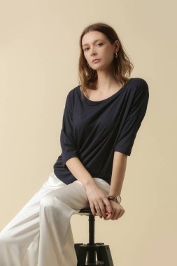 Siyah bluz ve beyaz pantolon giyen bir manken. Klasik ve basit moda. Stüdyo çekimi.