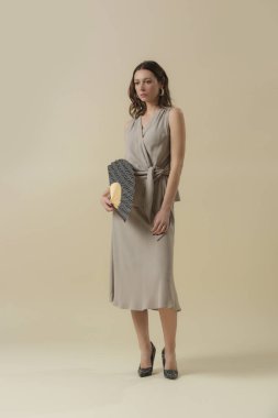 Stüdyo fotoğrafları, keten bej takım elbise, bluz ve etek giymiş genç bayan modeller. Gündelik ve şık kıyafetler, bahar-yaz moda trendi.
