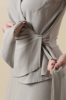 Stüdyoda keten bej V yaka bluzlu genç bir kadın modelin ciddi fotoğrafları. Gündelik ve şık kıyafetler, bahar-yaz moda trendi.