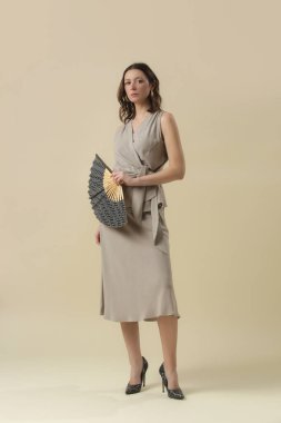 Stüdyo fotoğrafları, keten bej takım elbise, bluz ve etek giymiş genç bayan modeller. Gündelik ve şık kıyafetler, bahar-yaz moda trendi.