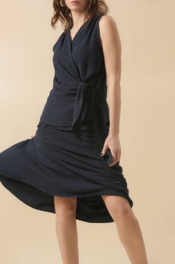 Stüdyoda keten mavisi takım elbise, bluz ve etek giymiş genç bir kadının fotoğrafları. Gündelik ve şık kıyafetler, bahar-yaz moda trendi.