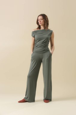 Loungewear pamuk giyen kadın model yumuşak ve rahat kıyafet, yeşil bluz ve pantolon. Klasik ve basit moda. Stüdyo çekimi.