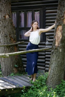 Beyaz bluzlu ve keten mavisi etekli bir kadın kırsalda huzurlu bir yaz gününün tadını çıkarıyor.