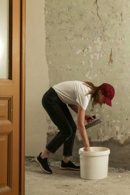 Duvarı macun bıçağıyla sıva yapan kadın. Firewall yüzeyi ve resim hazırlığı. DIY konut geliştirme projesi.