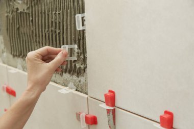 Banyo duvarlarını döşeyen kadın. Düz duvar plastik döşeme sistemi. Banyoya fayans döşeme işlemi. DIY Ev Geliştirme.