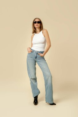 Klasik kıyafetli bir kadının stüdyo fotoğrafları. Mavi kot pantolon ve beyaz atlet.