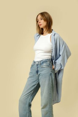 Klasik kıyafetli bir kadının seri fotoğrafları. Mavi kot pantolon, beyaz askılı bluz ve mavi pamuklu gömlek.