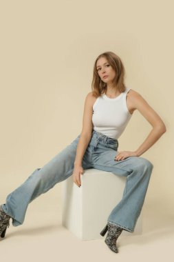 Klasik kıyafetli bir kadının stüdyo fotoğrafları. Mavi kot pantolon ve beyaz atlet.