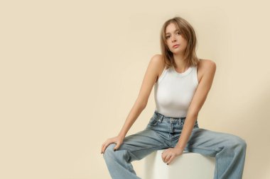 Klasik kıyafetli bir kadının stüdyo fotoğrafları. Mavi kot pantolon ve beyaz atlet.
