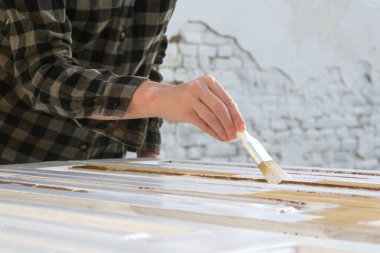 Beyaz renkli boya fırçasıyla ahşap kapı boyama işlemi, DIY ev geliştirme projesi.