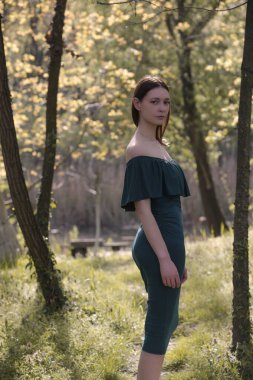 Yeşil yaz elbisesi içinde genç bir kadının portresi doğada sıcak yaz gününün tadını çıkarıyor. Yaz tatili konseri.