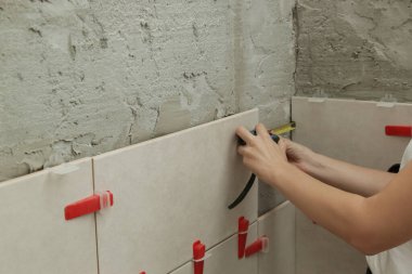 Banyo duvarlarını döşeyen bir kadın, uzunluğu ölçmek için mezura kullanıyor. Banyoya fayans döşeme işlemi adım adım yapılıyor. DIY Ev Geliştirme.