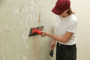 Duvarı macun bıçağıyla sıva yapan kadın. Firewall yüzeyi ve resim hazırlığı. DIY konut geliştirme projesi.