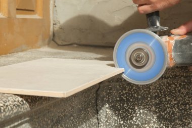 İşçi seramik fayansları disk öğütücü makinesiyle kesiyor. DIY ev geliştirme projesi.