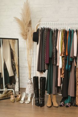 Kadın kıyafetleri ve ayakkabıları. Moda atölyesinde şık ve şık giysilerle elbise askısı. Kaliteli, zamansız moda eserleri. 