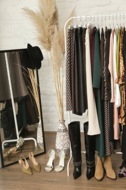 Kadın kıyafetleri ve ayakkabıları. Moda atölyesinde şık ve şık giysilerle elbise askısı. Kaliteli, zamansız moda eserleri. 