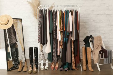 Kadın kıyafetleri ve ayakkabıları. Moda atölyesinde şık ve şık giysilerle elbise askısı. Kaliteli, zamansız moda eserleri. 