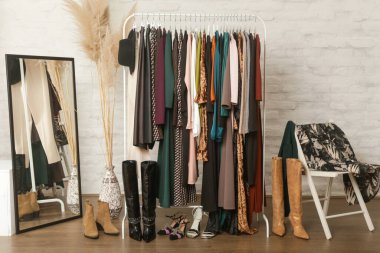 Kadın kıyafetleri ve ayakkabıları. Moda atölyesinde şık ve şık giysilerle elbise askısı. Kaliteli, zamansız moda eserleri. 