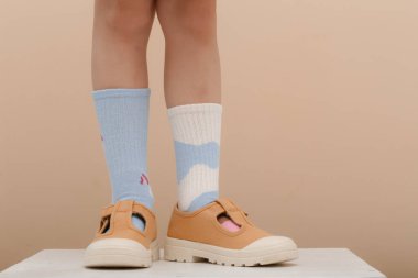 Çocuk farklı bir çift çorap giyiyor. Uyumsuz çoraplar, stüdyo fotoğrafçılığı. Down sendromu farkındalık konsepti, garip çoraplar günü, zorbalık karşıtı hafta.