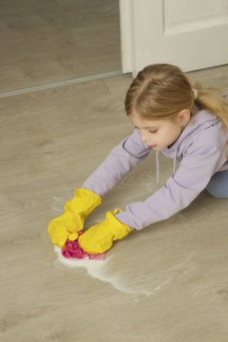 Yerleri ıslak bezle temizlerken koruyucu lastik eldiven takan sevimli küçük kız.. 