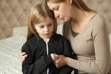 Sevgi dolu anne üzgün küçük kızını teselli ediyor.